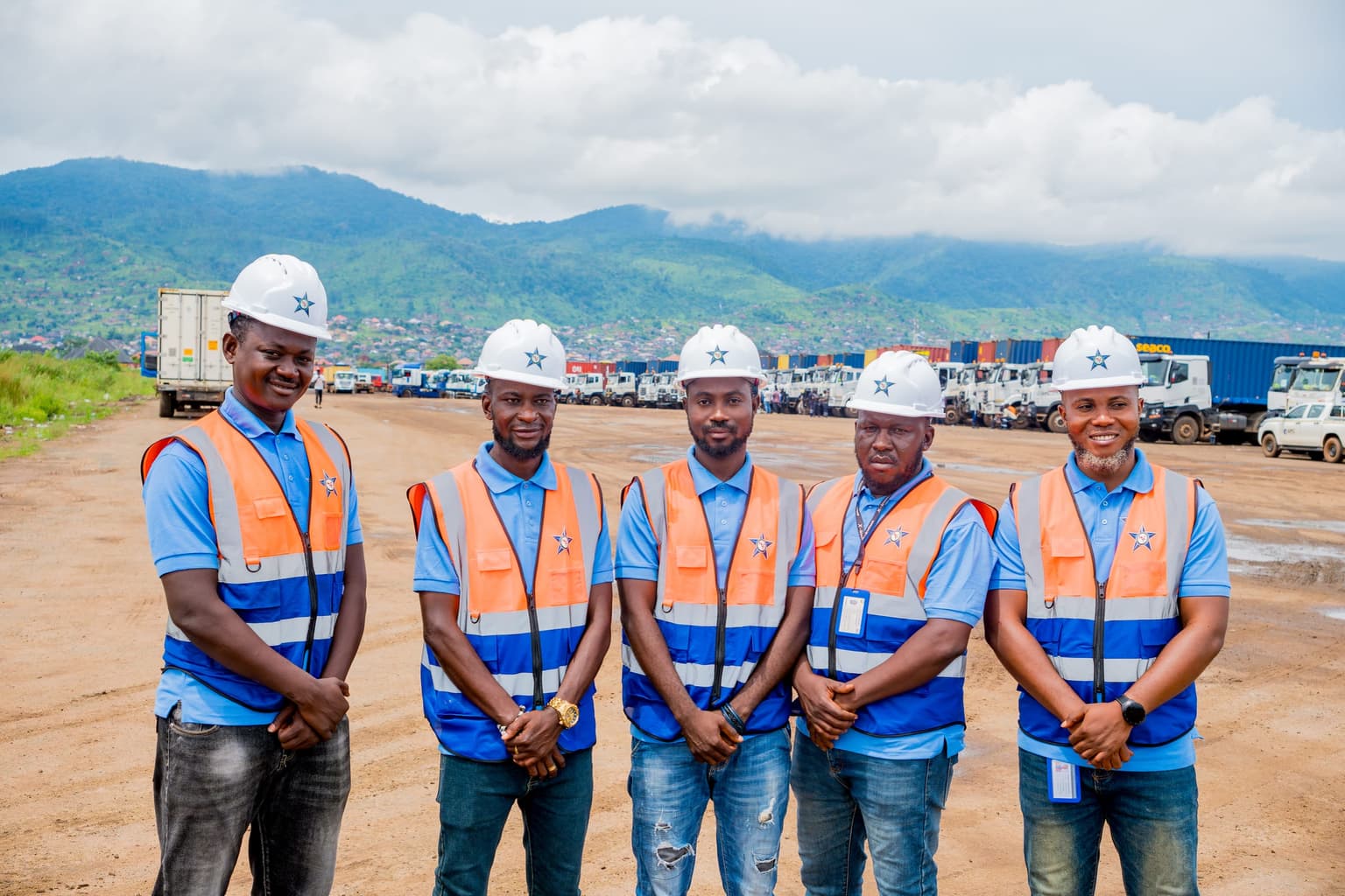 Nexus Logistics team on site at the Freetown depot, with the company truck fleet and surrounding hills in the background